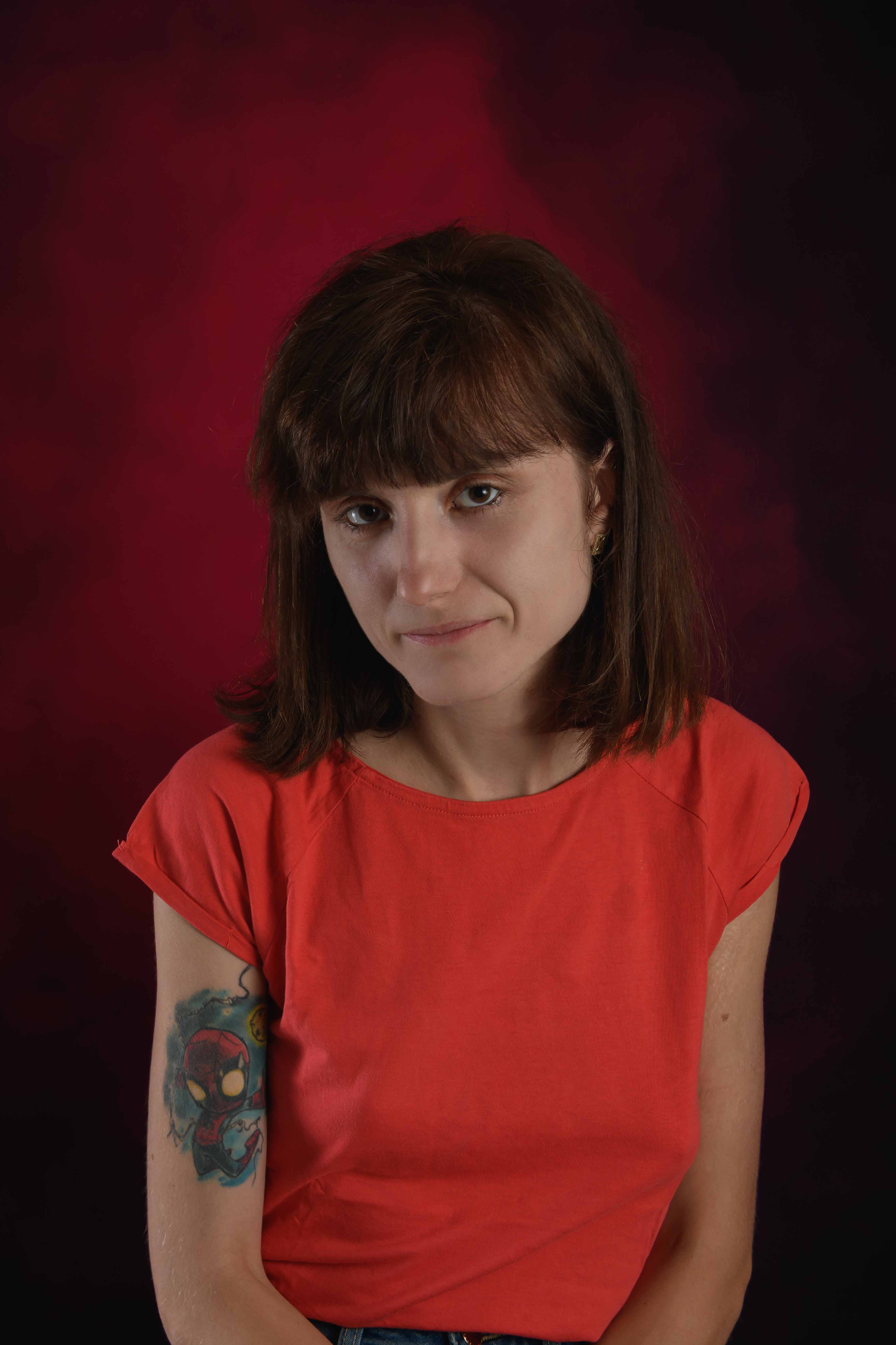 Portret kobiety podczas sesji fotograficznej w studio na czerwonym tle.