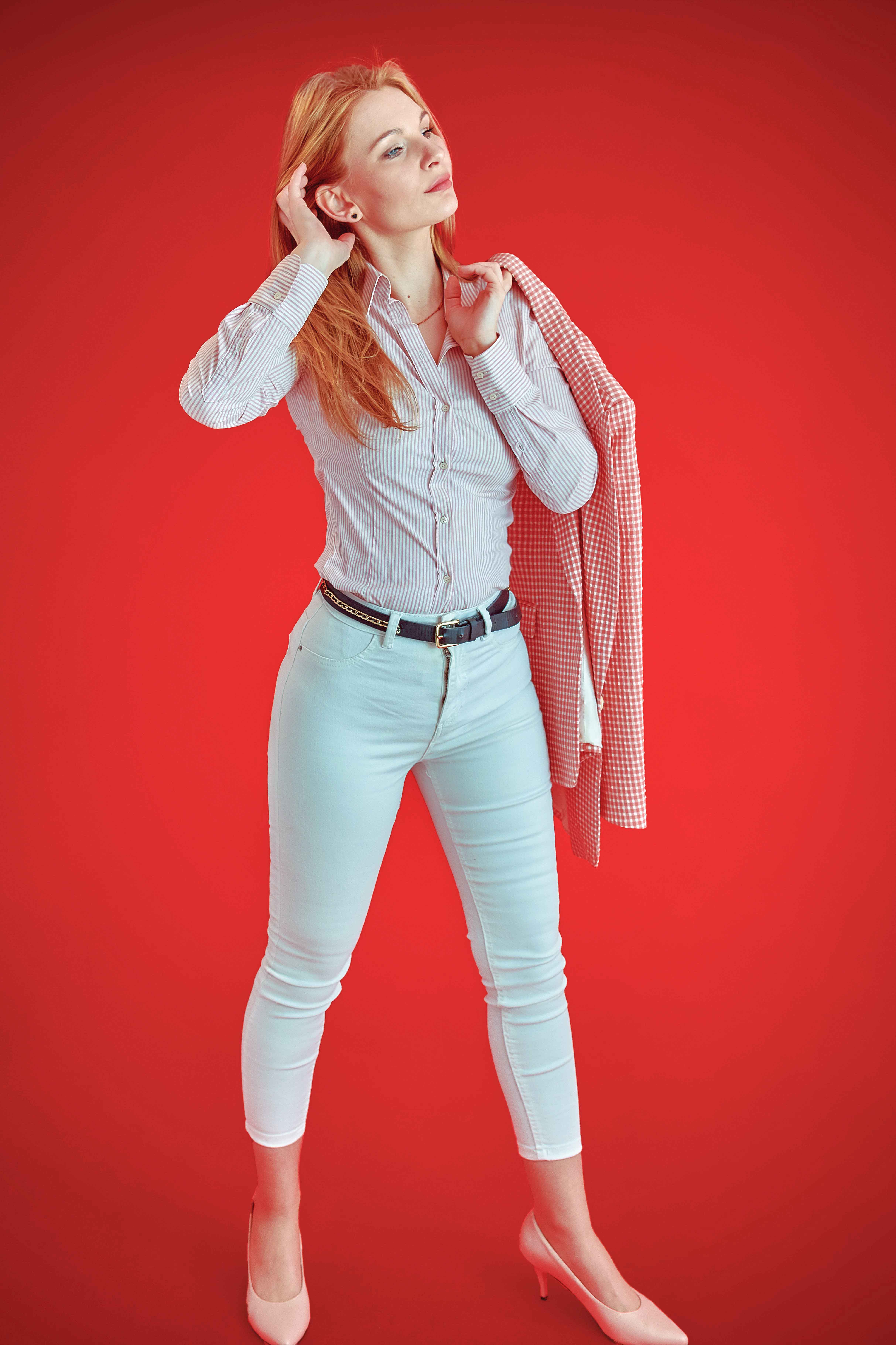Portret kobiety w eleganckiej stylizacji wykonany w studio na czerwonym tle